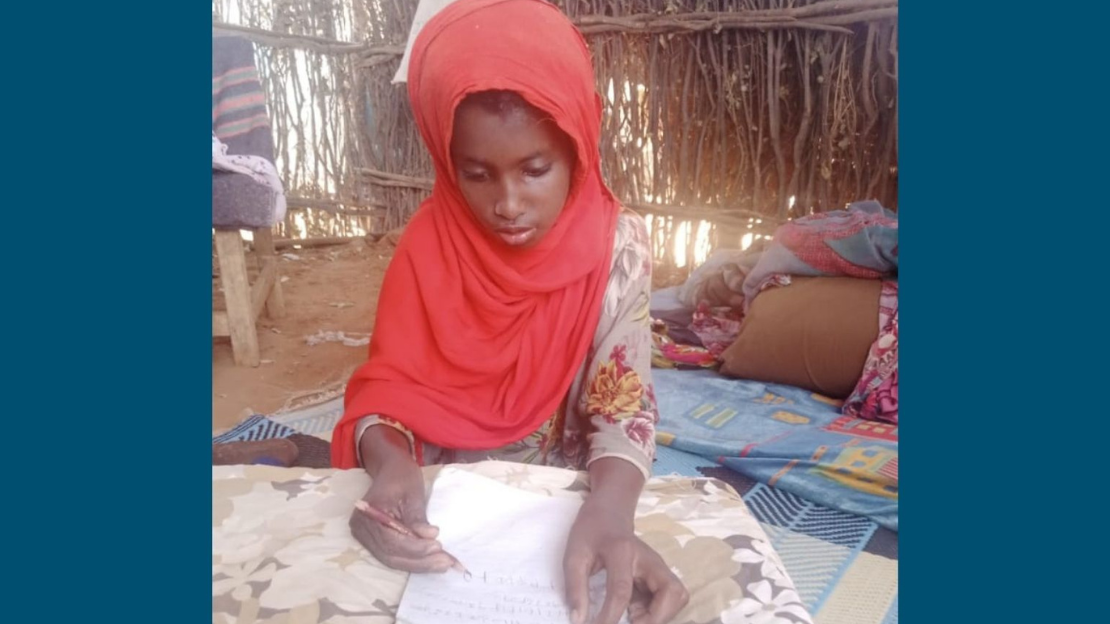 A young girl named Faiso writes with a pencil and paper inside her home in Kenya