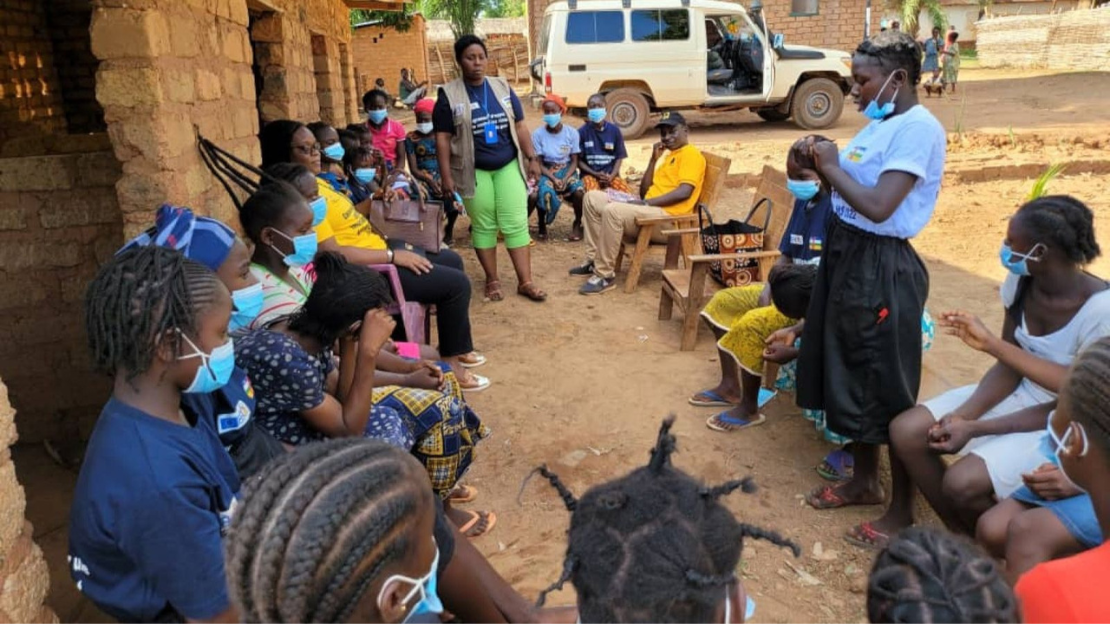 A group of women and girls gather in chairs in a circle. 