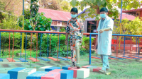 A Cambodian girl wearing an artificial leg walks over blocks with a rehabilitation specialist standing nearby
