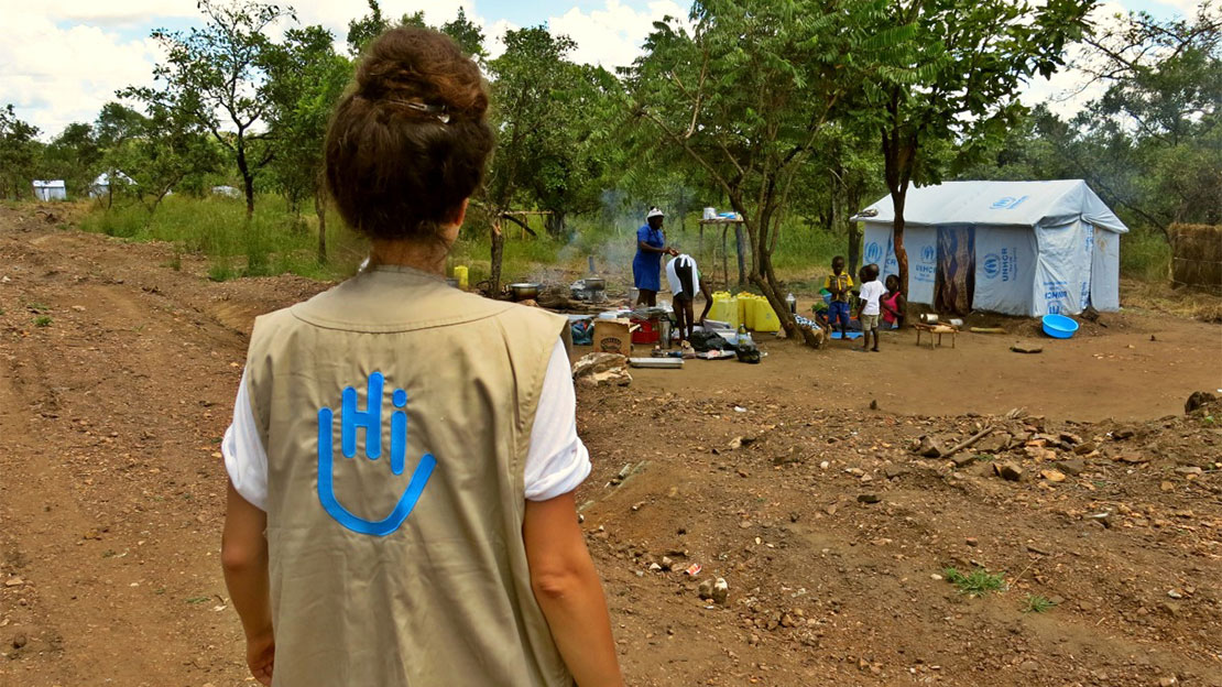 An HI field coordinator with a local family in a refugee settlement in Uganda 