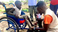 Beatrice, a young South Sudanese refugee girl being supported by James, an HI physical therapist.