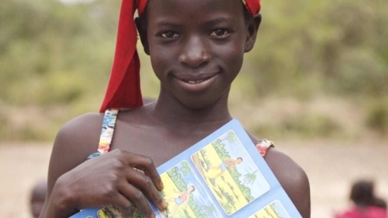 Having just attended an awareness raising session, 11-year-old, Awo Goudiaby holds up a leaflet with drawings depicted important safety messages. Senegal.