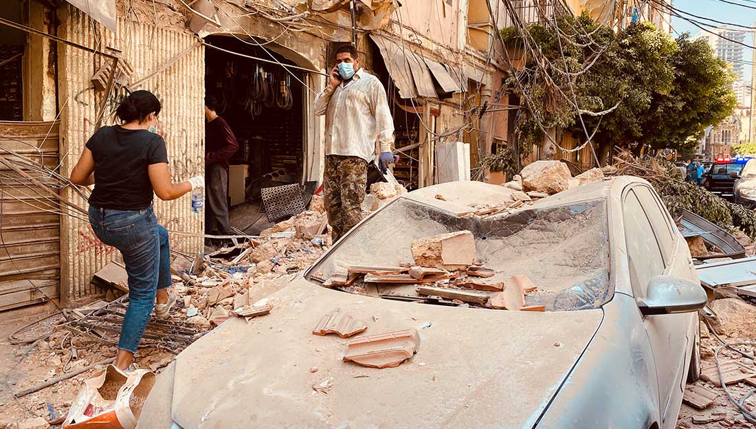 Beirut, Lebanon- August 5: People wearing face masks walks past damaged cars after Tuesday's massive explosion in Beirut, Lebanon. The blast hit Lebanese capital on August 4, with over 80 people killed and some 4,000 injured.