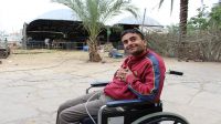 Odai outside in the yard, with the family farm behind him. Gaza.