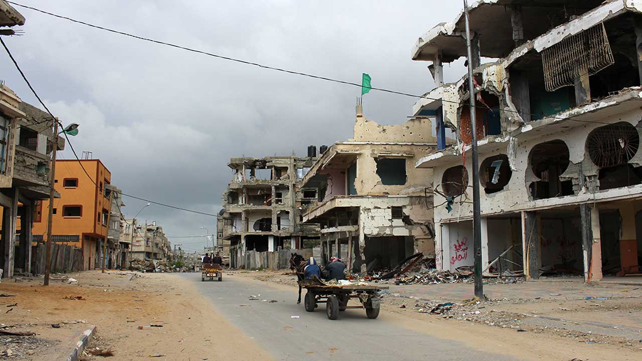 People on horse and cart pass buildings in Shejaiya, Gaza. The area is heavily contaminated with ERW and many people are still living amongst the rubble.