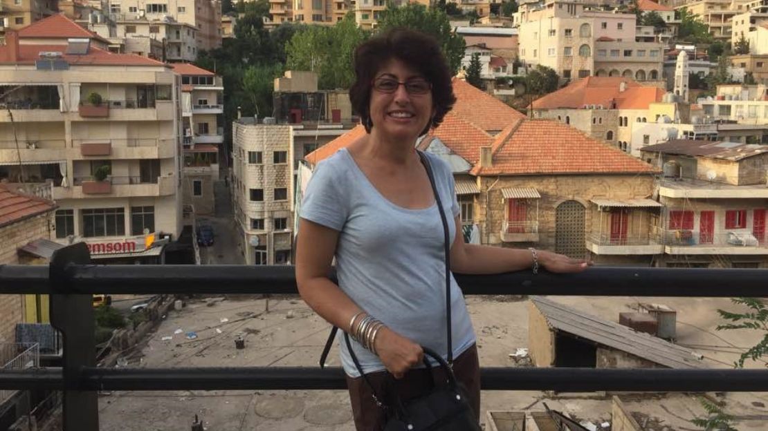 A woman stands at a railing with a cityscape behind her