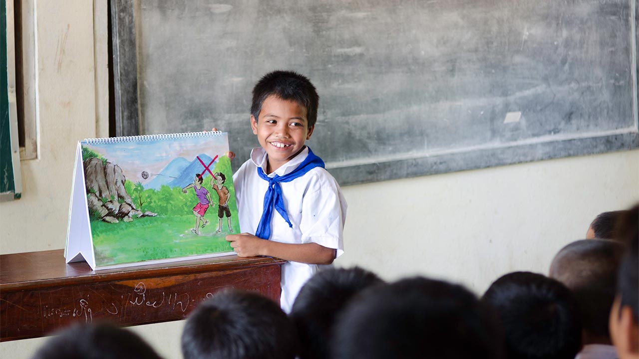A young boy explains the risks from UXO to his classmates during a risk education session in Pounseeyerng village, Laos.