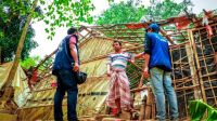 Three men outside a shelter constructed of bamboo and tarps