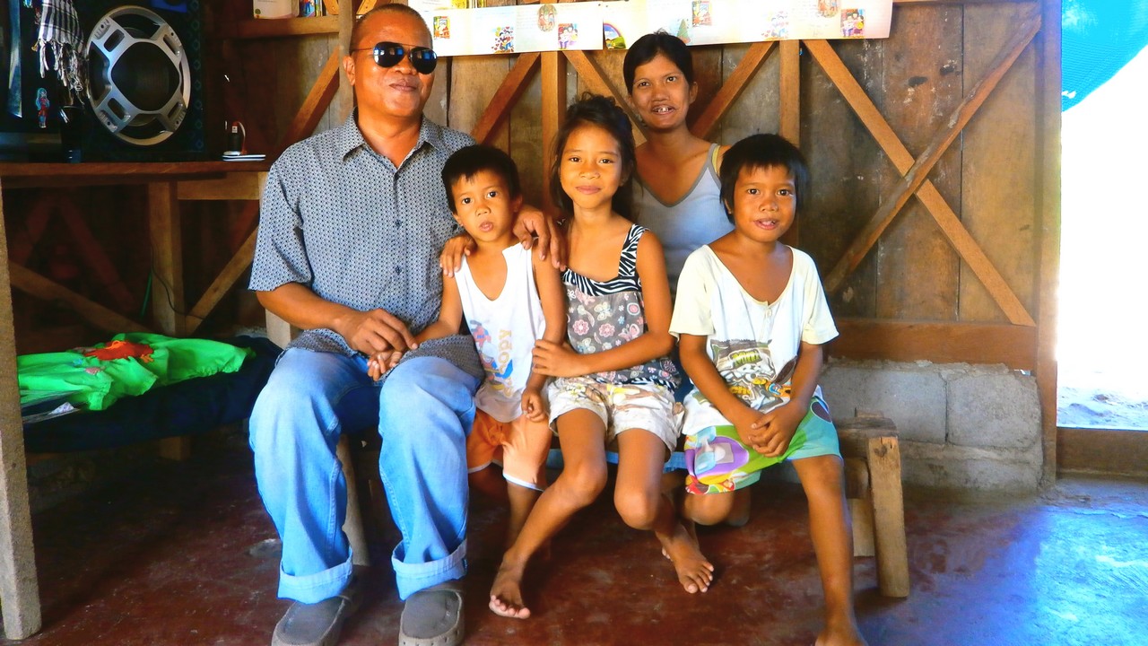Renato, his wife and three of their six children in their newly repaired home. The Philippines.