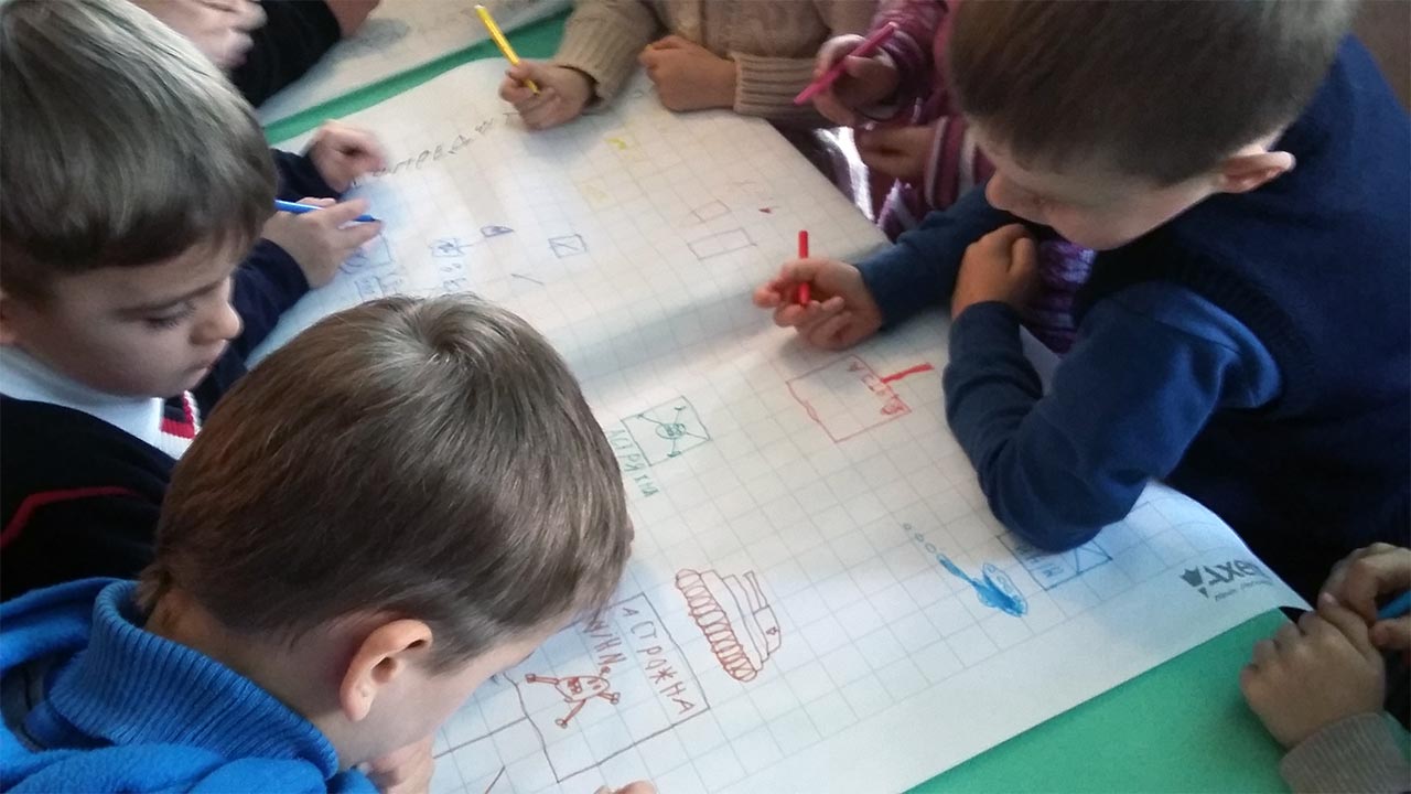 Children drawing situations where they might encounter mines, during a risk education session in Ukraine 